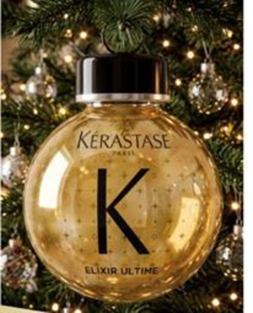 Gold Kérastase-branded Christmas bauble hanging on a lit tree